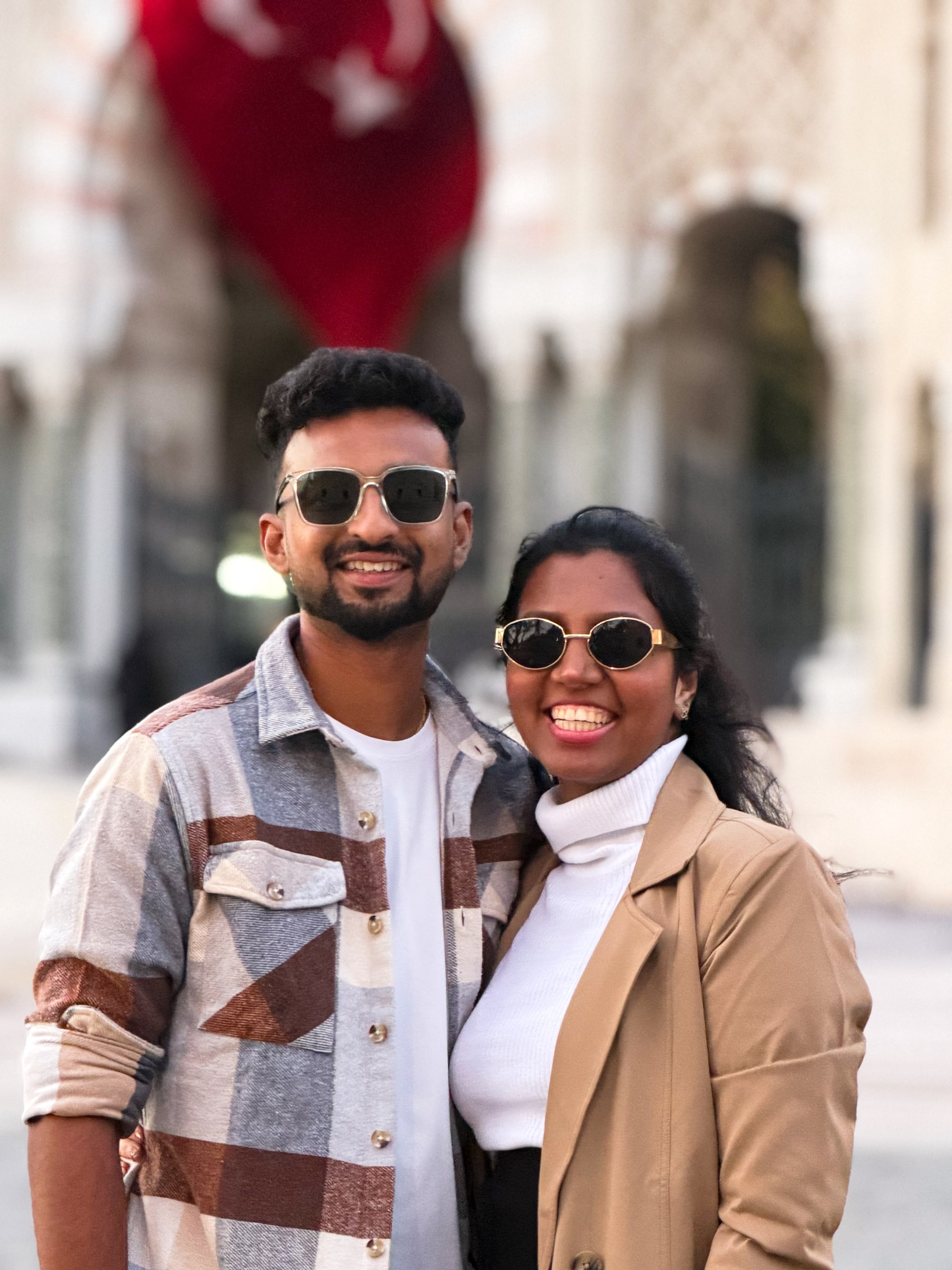 Santhosh (left) and Priya, the founders of Dream On Travel, smiling together in sunglasses on a trip.